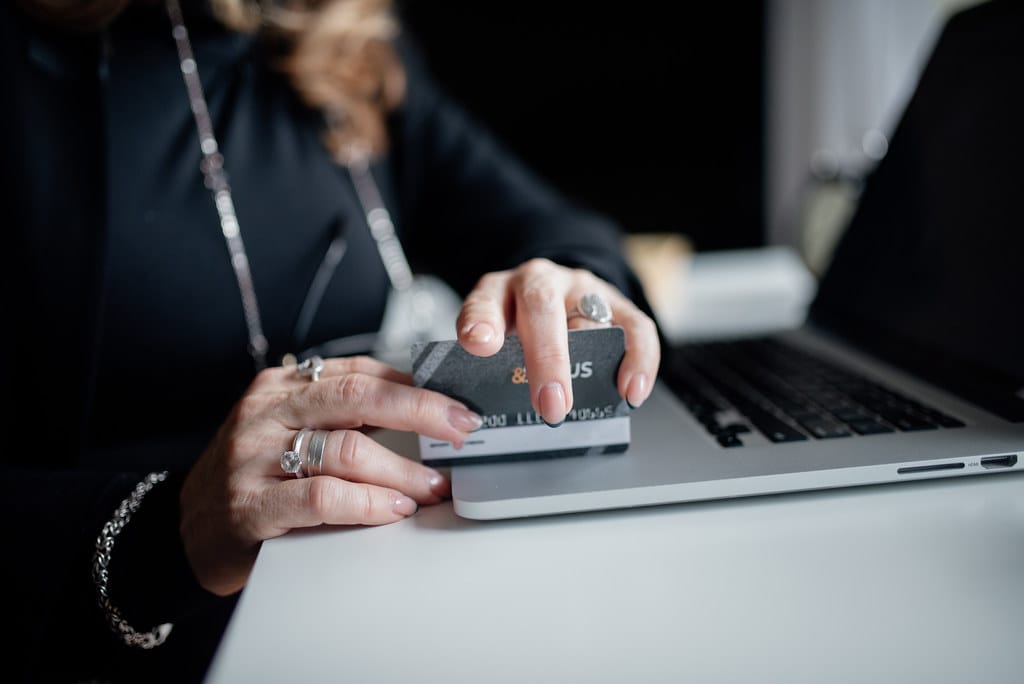 Live checkout verification A shopper completing an online purchase with a credit card at a laptop, representing the live checkout moment an AI shopping agent's session must also pass